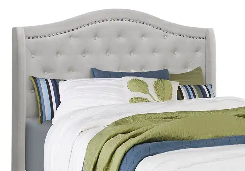 Lit capitonné à oreilles en velours gris avec des clous décoratifs et des boutons touffus